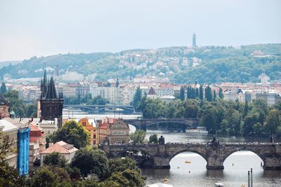 Arch bridge over river amidst buildings against sky