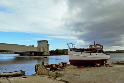 Boat moored on river against cloudy sky