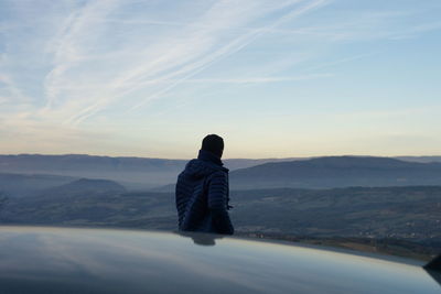 Rear view of man on mountain against sky during sunset