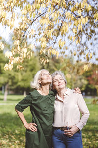 Full length of happy woman standing against plants