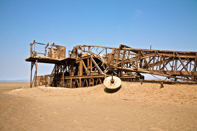 Cart on sand against clear sky