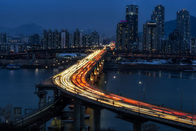 Illuminated bridge over river at dusk