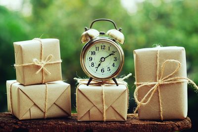 Close-up of gift boxes and alarm clock on wood outdoors