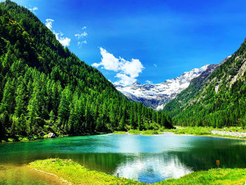 Scenic view of lake and mountains against blue sky