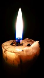 Close-up of burning candle against black background