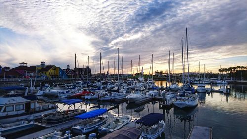 Boats moored in harbor at sunset