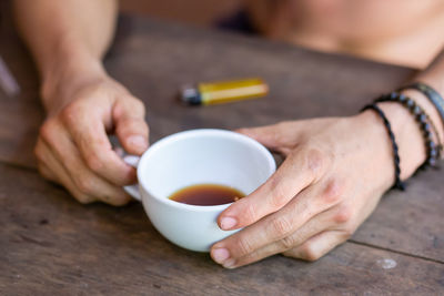 Midsection of woman holding tea cup on table
