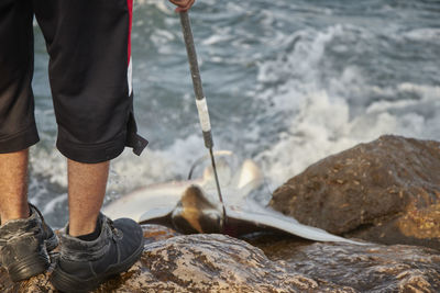 Low section of man standing on rock in sea