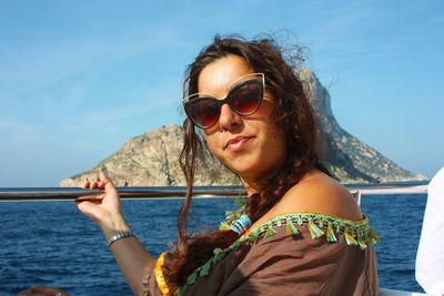 Caucasian girl traveling by boat on the ibizan sea and a rocky cliff behind in balearic island