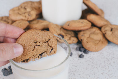 Cropped hand holding cookie with milk glass