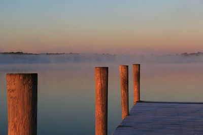 Pier over sea against sky during sunset