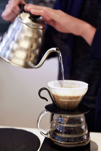 Midsection of person preparing coffee on table