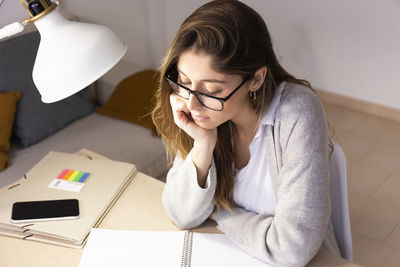 Young woman with book studying at home