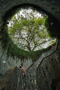 Low angle view of young woman amidst trees