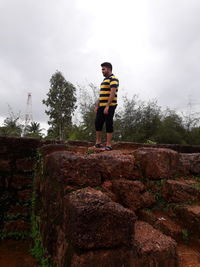 Low angle view of man standing by tree against sky