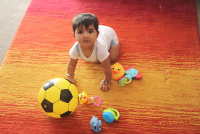 Portrait of boy playing with ball on floor