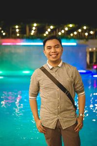 Portrait of young man standing against swimming pool