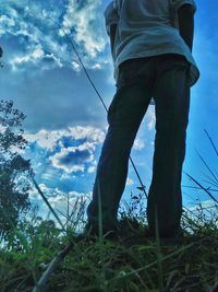 Low section of man standing on field against sky