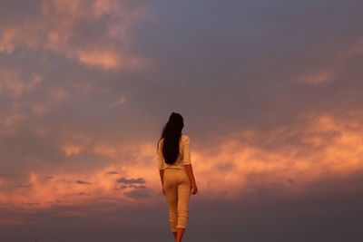 Young woman against sky at sunset