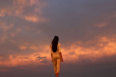 Young woman standing against sky during sunset