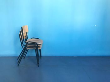 Empty chair on table against blue wall