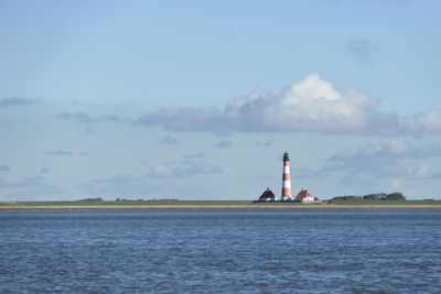 Lighthouse by sea against sky