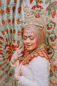 Woman in traditional clothing standing by curtain