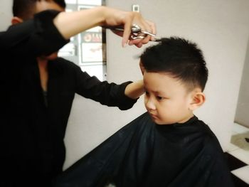 Man cutting boy hair at barber shop