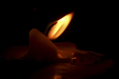 Close-up of illuminated candle in darkroom