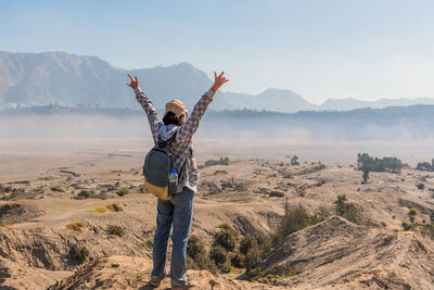 Woman standing on rock formation against sky