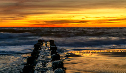 Scenic view of sea against dramatic sky during sunset