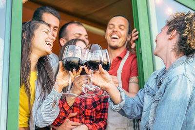 Happy friends toasting wineglasses during social gathering