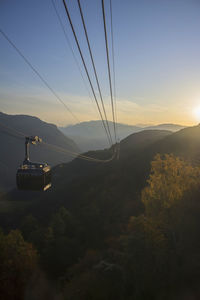 Overhead cable car on mountains against sky during sunset