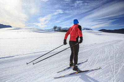 Rear view of man skiing on field against sky