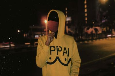 Portrait of person holding umbrella standing in city at night