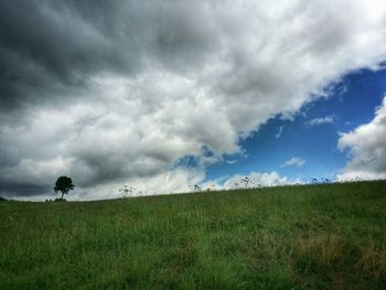 Scenic view of grassy field against cloudy sky