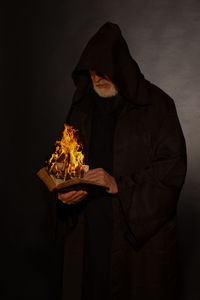 Midsection of man holding burning at night