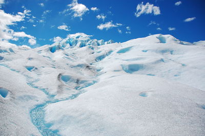 Snow covered landscape against blue sky