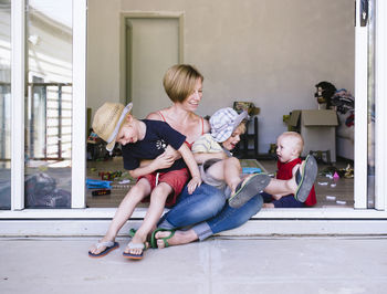 Mother playing with children while sitting on doorway at home