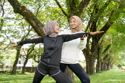 Smiling young woman with arms raised in park