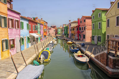 Boats moored in canal amidst buildings in city