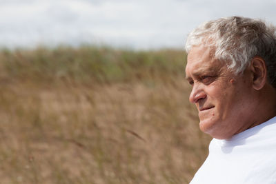 Mature man looking away while sitting on field