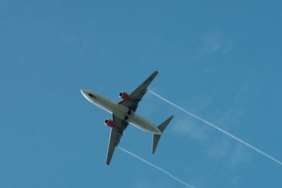 Low angle view of airplane flying against blue sky