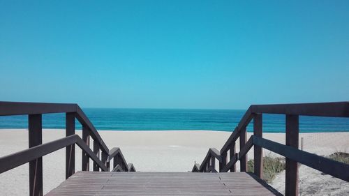 Pier over sea against clear blue sky