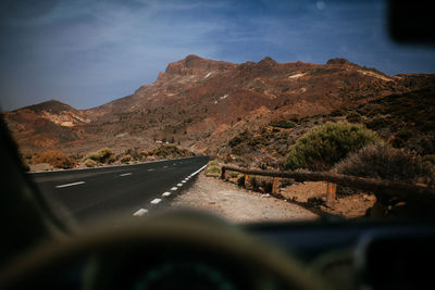 Road amidst mountains seen through car windshield