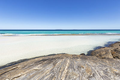 Scenic view of beach against clear blue sky