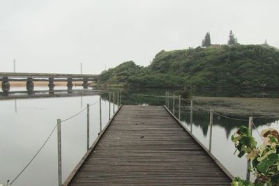 Bridge over calm lake against sky