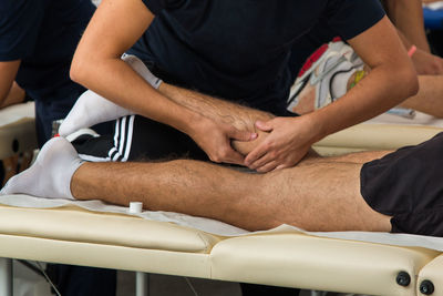 Midsection of man giving massage to athlete lying on bed