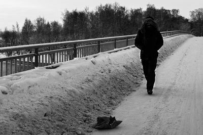 Rear view of woman walking on snow covered footpath