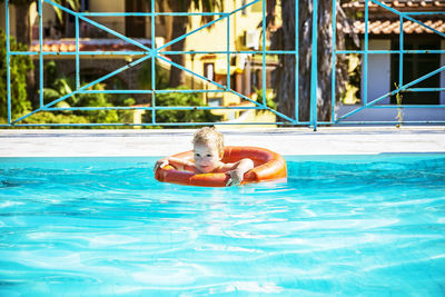 Cute boy swimming in pool on sunny day